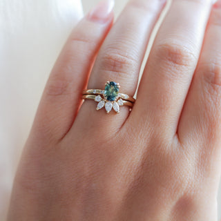 Yellow gold crown contour band with white diamonds and a yellow gold ring with an oval green sapphire, on hand