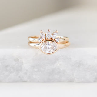 Yellow gold crown contour band with white diamonds and a yellow gold ring with an oval white diamond, front view