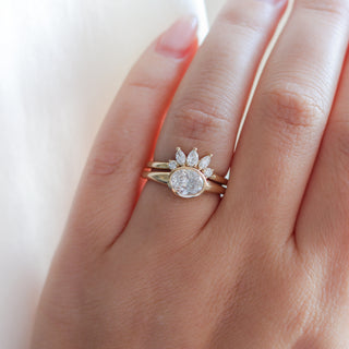 Yellow gold crown contour band with white diamonds and a yellow gold ring with an oval white diamond, on hand