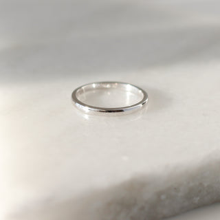 White gold 2mm band on white background in sunlight, front view