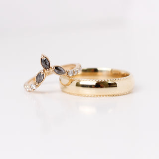 Two yellow gold wedding bands, one wide band with a rope edge and one thin pointed crown style band with salt and pepper diamonds forming the point and white round diamonds pavee style.  
