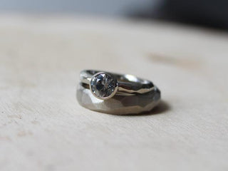 Faceted Wide Band in wihte gold stacked with round diamond ring quarter view