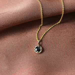 Round Black Diamond Sun Necklace on orange fabric