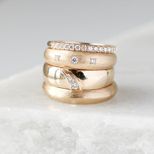 Textured Edge Gold Band stacked with shooting star diamond ring and dome diamond ring and diamond stacking band on marble