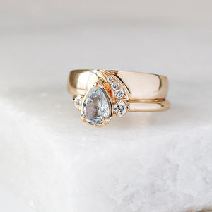 Shooting Star Diamond Wide Band stacked with pear diamond gold ring on marble quarter view