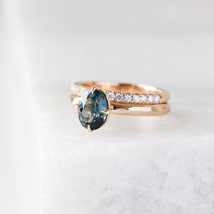Diamond Pave Gold Band stacked with oval sapphire ring on marble quarter view