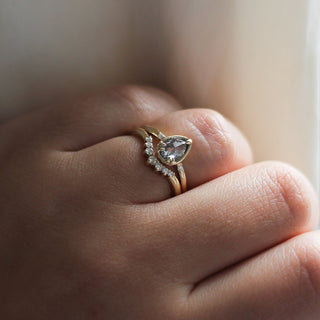 Pear diamond ring in yellow gold paired with diamond gold stacking band on hand