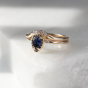 5-stone Diamond Wave Band stacked with blue sapphire ring on marble quarter view