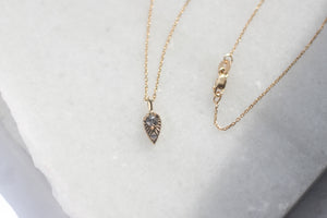 Tear Drop Diamond Sun Necklace with chain detail view on marble