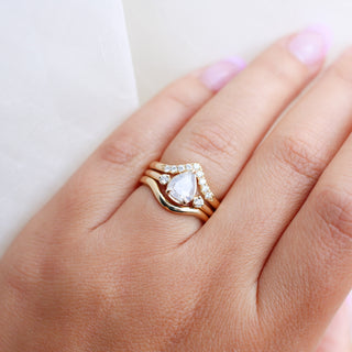 Pear icy diamond engagement ring with wedding bands on hand