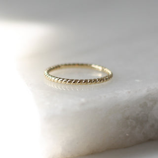 Twisted Thin Gold Band side view on marble
