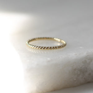 Twisted Thin Gold Band side view on marble