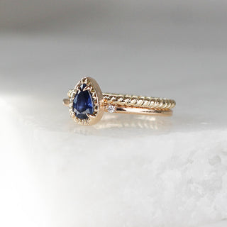 Twisted Thin Gold Band stacked with sapphrie ring quarter view on marble 