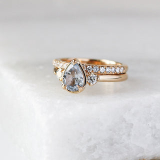 Diamond pave straight band stacked with pear diamond ring quarter view on marble